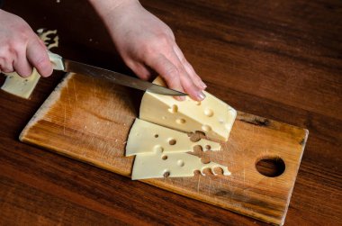 Tahtada peynir dilimlemek. Ürünlerin buzdolabında depolanması için hazırlama.