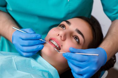 Tanımlanamayan beyaz kadın diş tellerini fırçayla temizliyor. Parantezli kadın dişlerinin yakın çekimi