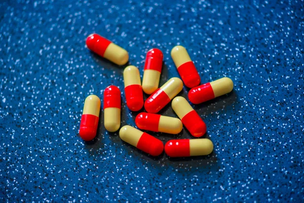 青色の背景に赤と黄色のカプセル薬 — ストック写真