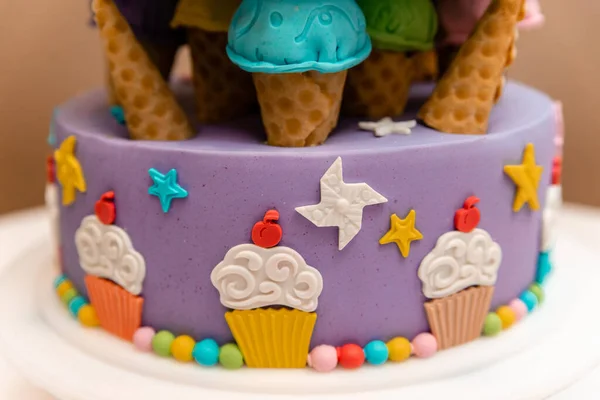Beautiful multi-colored children\'s cake from several layers decorated with sweets.