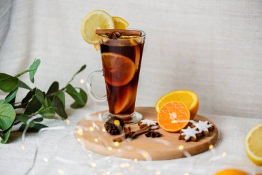 Sıcak şarap, mavi çam ağacı dalı ve ahşap arka planda baharatlar.