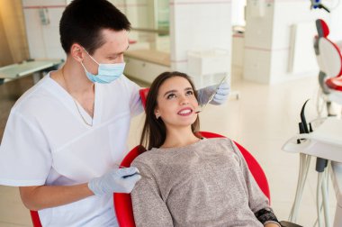 Doktor dişçi genç ve güzel bir kızın dişlerini tedavi ediyor. Dişçinin resepsiyonundaki kız. Doktor dişçi dişleri tedavi eder..