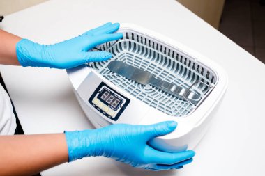 Klinikteki sterilizasyon odasında beyaz otoklav. Sistem steril çeliğe. Cerrahi ve dişçilik ekipmanları. Tıbbi aletler. Mavi eldivenler