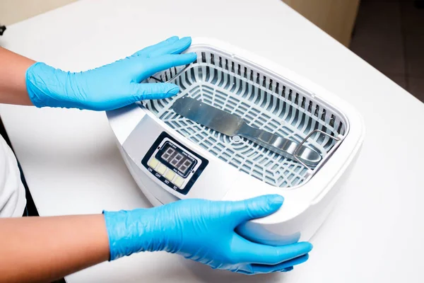 Klinikteki sterilizasyon odasında beyaz otoklav. Sistem steril çeliğe. Cerrahi ve dişçilik ekipmanları. Tıbbi aletler. Mavi eldivenler