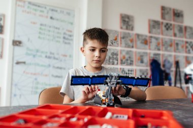 Göğsünde fiyonk olan bir tasarımcıdan bir çocuk ve bir robot bir araya geldi. Bir hediye ve bir arkadaş. Robot Bilimleri Okulu. STEM eğitimi.