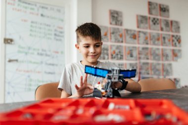 Göğsünde fiyonk olan bir tasarımcıdan bir çocuk ve bir robot bir araya geldi. Bir hediye ve bir arkadaş. Robot Bilimleri Okulu. STEM eğitimi.