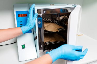 Manikürcü aletlerini elektrikli fırında sterilize ediyor. Öğretmenim salonda aletlerini dezenfeksiyon için hazırlıyor..