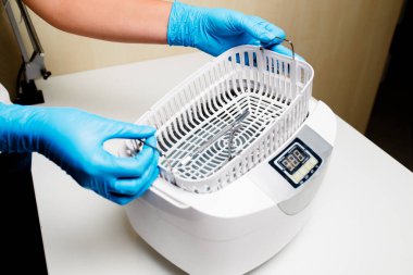 Bir kadın su sterilizatörüne aletler koyar. Enstrümanların sterilizasyonu.