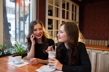 Kahve içme ve telefonda konuşurken iki güzel kız