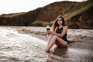 Yunanistan 'da yoğun bir yaz günbatımında Akdeniz manzaralı bir bardak şarabın keyfini çıkaran bir kadın görülüyor