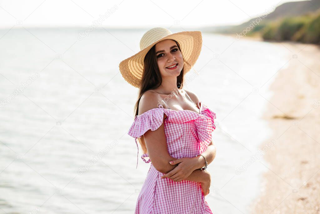 Bride holds wedding beautiful bouquet of flowers on background of sea. Girl is dressed in blue wedding dress and hat.