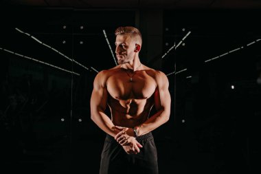 Karanlık Arkaplanda Kaslı Model Genç Adam. Moda tarzı saç stili olan güçlü kaba adamın moda portresi. Seksi Çıplak Gövde, Altı Paket Abs. Erkek kaslarını esnetiyor. Spor Vücut Geliştirme Konsepti.