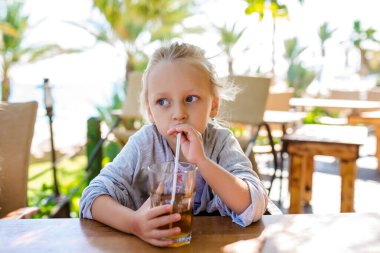 Eğlenceli sevimli çocuk kız sokak restoranda sağlıklı güler yüzlü suyu içme. Tonda portre portre