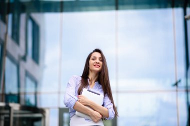 İş kadını ofis binasının önünde tablet bilgisayar kullanıyor