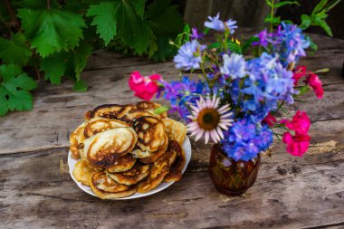 Ahşap bir arka planda çiçekler eşliğinde pişirme ve çilekler