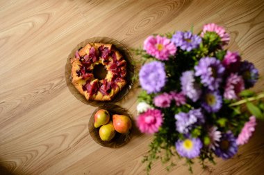 Elmalı turta, armut ve çiçekler masada.