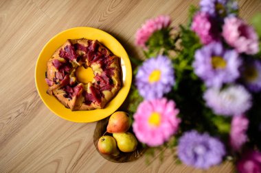 Elmalı turta, armut ve çiçekler masada.