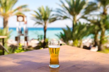 Denize karşı tahta bir masada bir bardak bira.