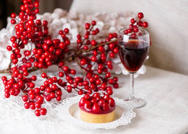 Bir bardak kırmızı şarap, şeker ve kırmızı böğürtlenli bir dal.