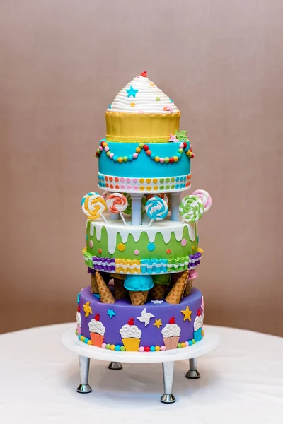 Beautiful multi-colored children's cake from several layers decorated with sweets