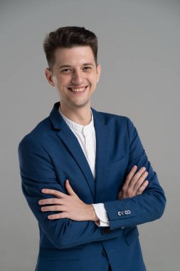 Gri arka planda soyutlanmış yakışıklı, çekici, gülümseyen iş adamı.