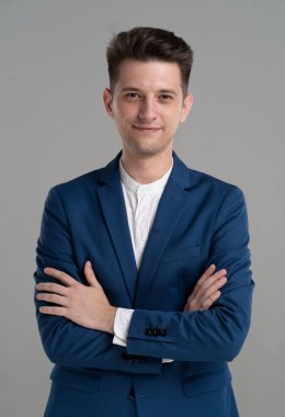 Gri arka planda soyutlanmış yakışıklı, çekici, gülümseyen iş adamı.