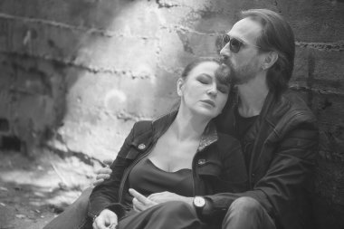 Güneş gözlüklü şık bir adam tatlı karısına nazikçe sarılıyor.