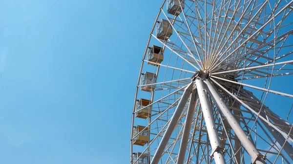 Mavi gökyüzüne karşı dönme dolap. Temiz mavi gökyüzünün arka planında büyük beyaz dönme dolap.