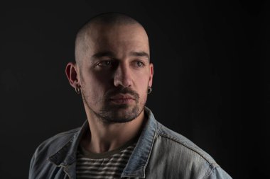 Denime 'deki sakin bıçaklı adamın portresi stüdyoda siyah arka planda dikilirken düşünceli bir şekilde kenara bakıyor.