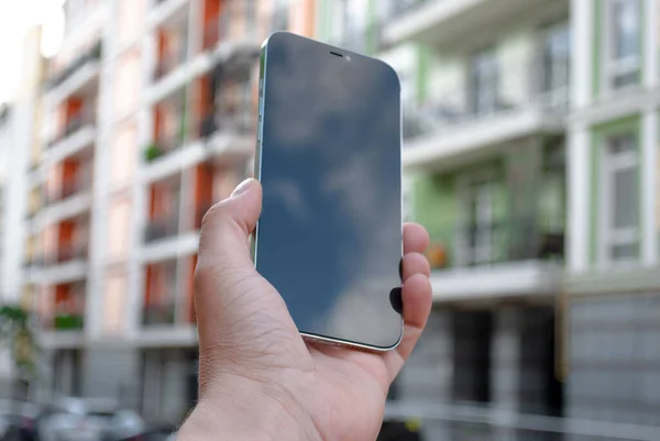 Close up of mobile with black screen with sky reflection. Using contemporary smartphone, blurred building background. Blank screen ready for your business ideas.