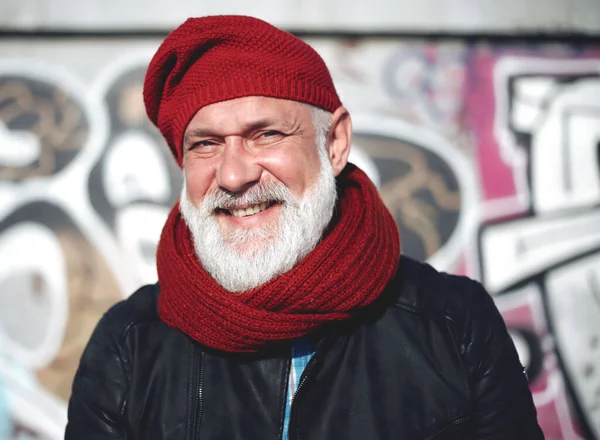 Happy senior bearded man in red knitted hat and scarf portrait. Attractive old man with white beard