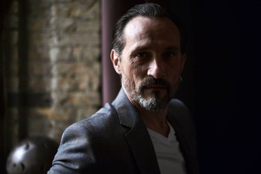 Gün ışığında bir yüzü olan yakışıklı bir erkek portresi. Işık profilli bir insan portresi. Siyah arka planda yan görüş. Işık ve brik arka planında insan portresi