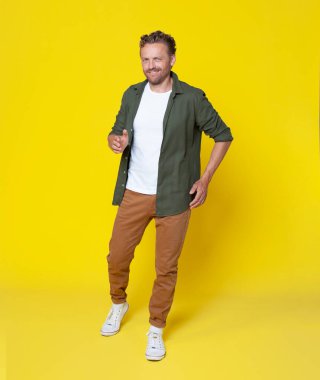 Full length body size image of man wearing casual outfit walking and smiling isolated on yellow color background. Handsome man dancing