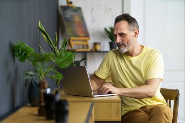 Evden dizüstü bilgisayarda çalışan bir adam. Finansal veriler sayılıyor. Orta yaşlı, sakallı bir girişimci. Dairenin içindeki bir masada oturmuş bilgisayarda daktilo yazıyor.