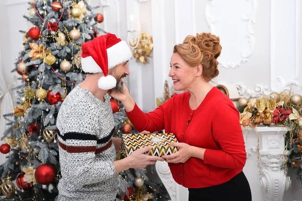 Family couple celebrating season holiday together. Pleased lovely woman tenderly touching her mans face in gratitude for Christmas present. Charming positive couple exchanging gifts.