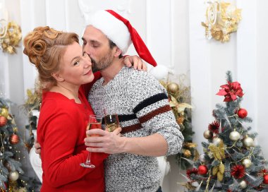 Noel partisinde birbirini kucaklayan pozitif bir çift. Sevgili kocası bir kadeh şampanya içerken karısının yanağını öpüyor ve kendini rahatlamış hissediyor.