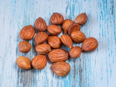 Heap of brown apricot kernels on vintage wooden background Macro shot