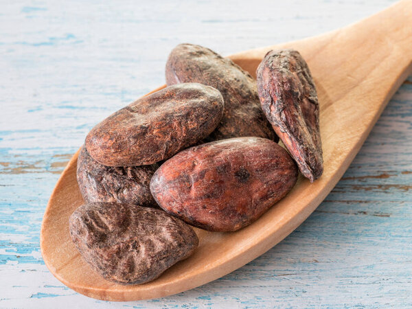 Aromatic cocoa beans and spoon  on wooden table. Macro shot