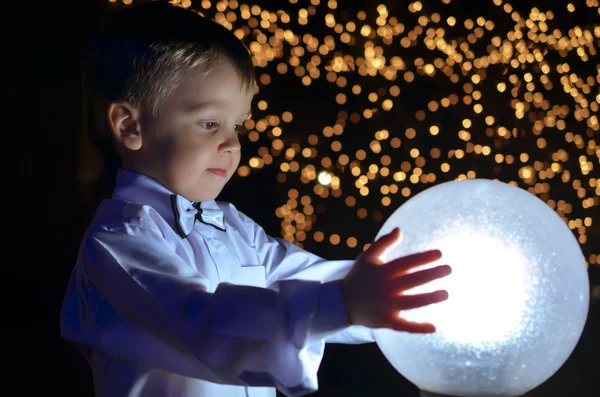 Pojken håller en glödande boll. — Stockfoto