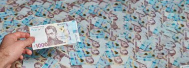Ukrayna parası. Ukrayna parasının geçmişi. Banknotların afişi. El Ukrayna 1000 Hryvnia 'sını tutuyor..