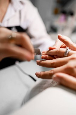 Bir kız manikür yapıyor. Tırnak törpüsü yakın plan. Jöle cilası, oje, tırnak cilası..