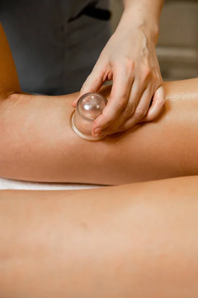 Massage with vacuum cups on the leg of a girl close-up. Vacuum therapy with massage jars.