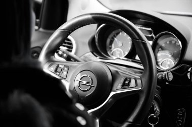 Almanya, Bocholt, 28 Nisan 2022: Kız direksiyonu çeviriyor. Siyah beyaz resim. Genç bir kadın Opel 'in direksiyonunu çeviriyor.