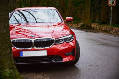 Almanya, Bocholt, 28 Nisan 2022: Kırmızı bir BMW yolun kenarında bir ağacın üzerinde duruyor. BMW bir ağaca çarptı. Hız sınırı işareti ve BMW