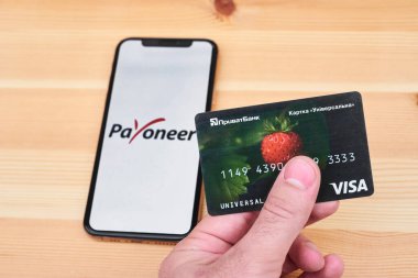 Ukraine, Kyiv, May 3, 2022 - PrivatBank card on the background of the flag of Ukraine and the payoneer logo. payoneer app icon. payoneer launches in Ukraine