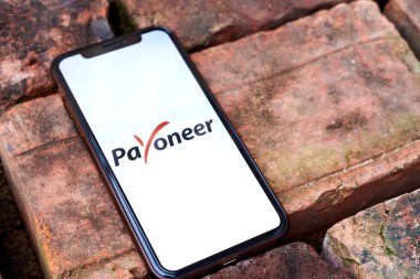 Ukraine, Kyiv, May 3, 2022 - Smartphone with payoneer logo lies on a brick background. Space for text