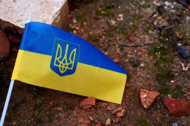 The flag of Ukraine lies on the ruins of a broken brick close-up