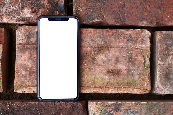 Mobile phone template with white screen. The smartphone lies on the texture of the brick. Mockup of a mobile phone — 스톡 사진