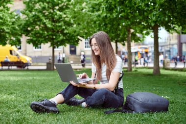 Serbest çalışan biri dizüstü bilgisayarda çalışır. Kız temiz havada uzaktan bilgisayarla çalışıyor.. 