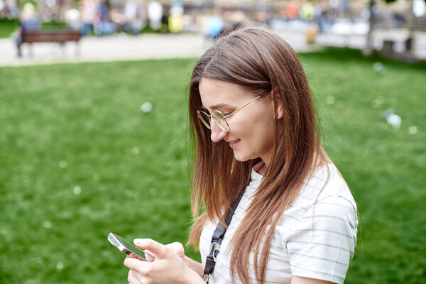 Девушка на свежем воздухе смотрит на телефон